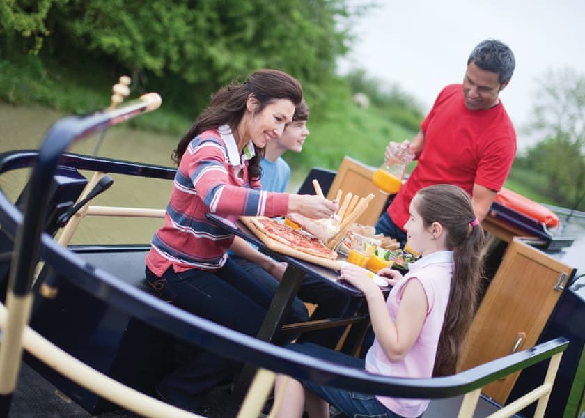 A family enjoying breakfast together on a narrowboat rear deck.